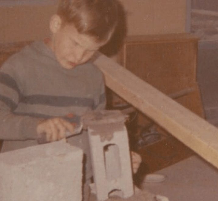 Steve Miller at about age eight, spreading mortar with a trowel, fourth-generation Michigan mason and founder of The Stone Mill