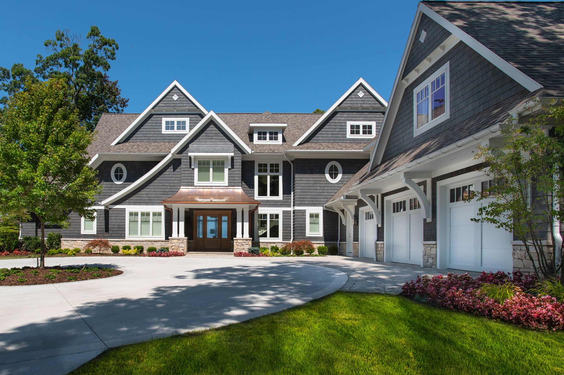 Black River Ashlar stone wainscot and entry piers on a shingle-style home by Mike Schaap Builders