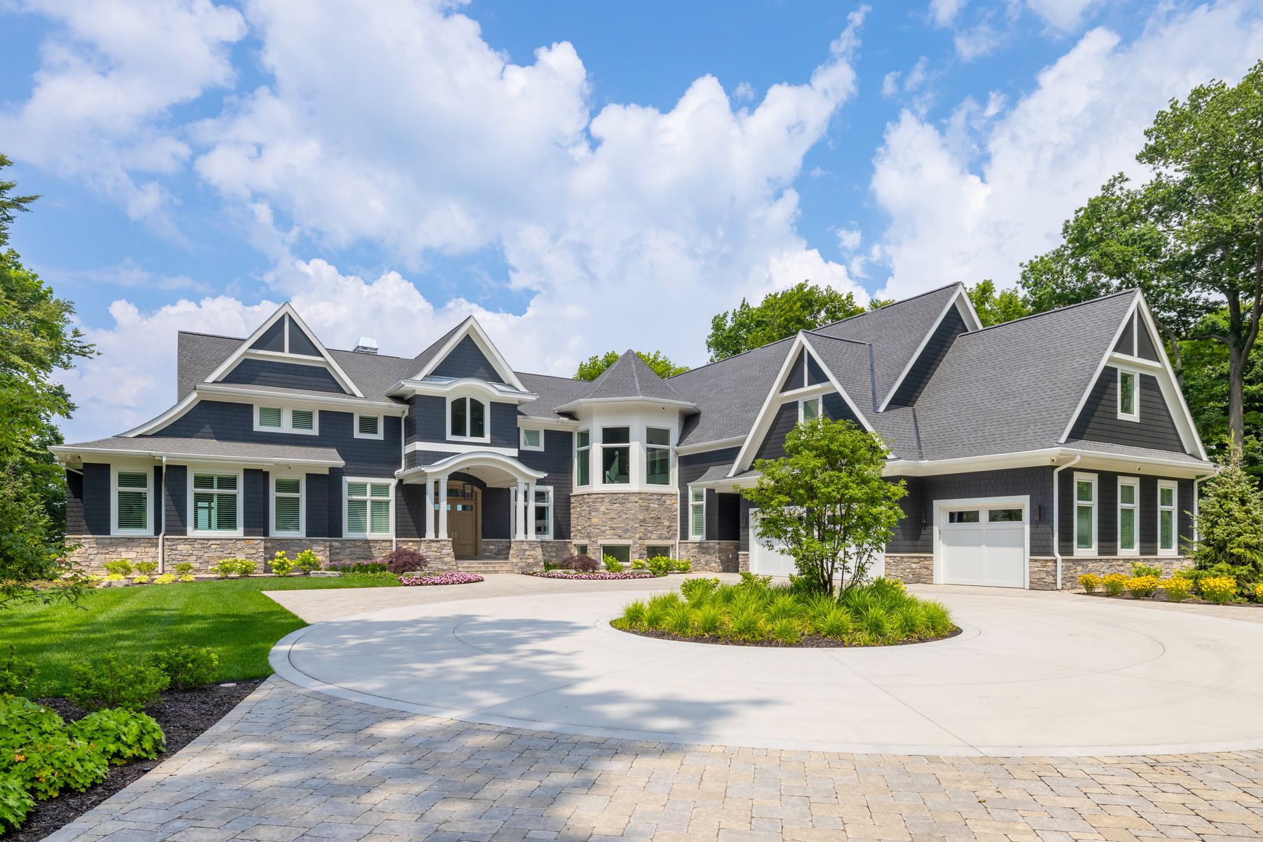 Black River Ashlar stone wainscot, turret base, and entry piers on a shingle-style home by Mike Schaap Builders